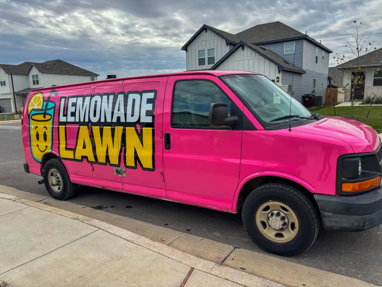 Pink Lemonade Lawn Care van parked on a street in a new New Braunfels subdivision